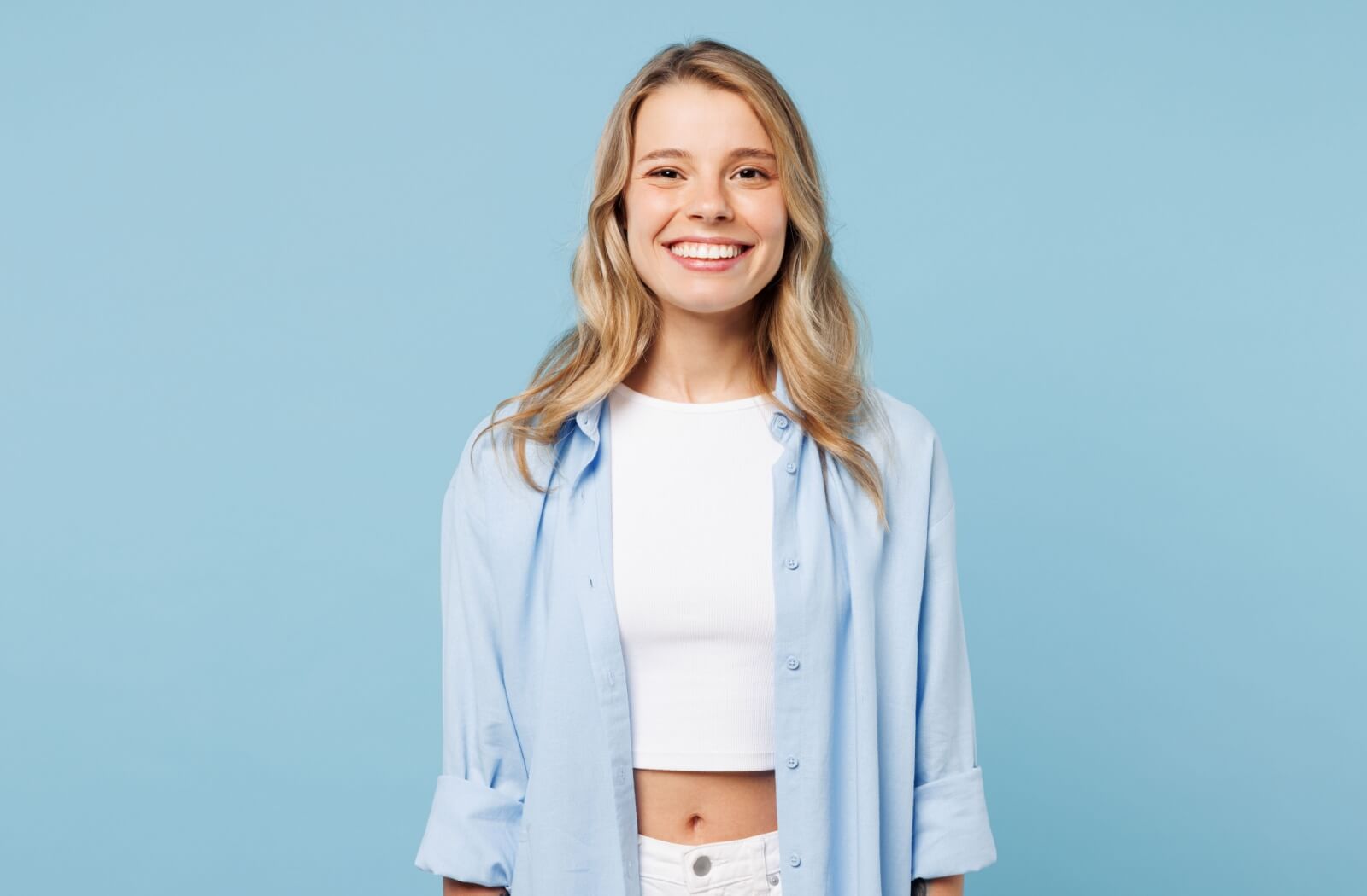 A person with white teeth standing and looking happily towards the camera.